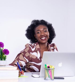 A cheerful African businesswoman working at her desk in Kinshasa, showcasing a lively professional workspace.